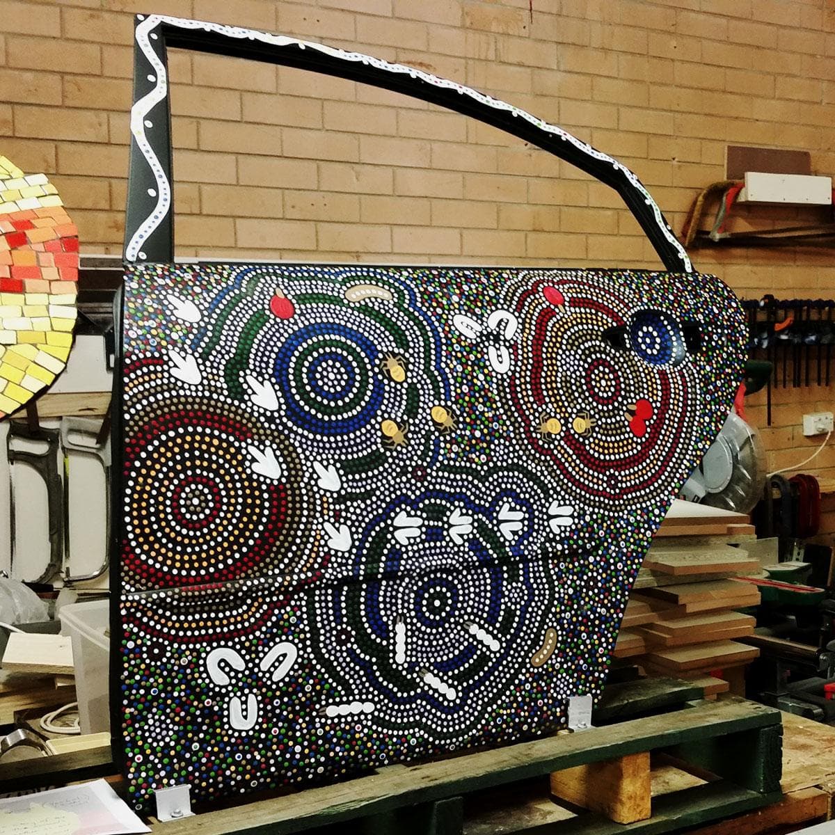 Wooden car door panel with Indigenous dot art painted on the side