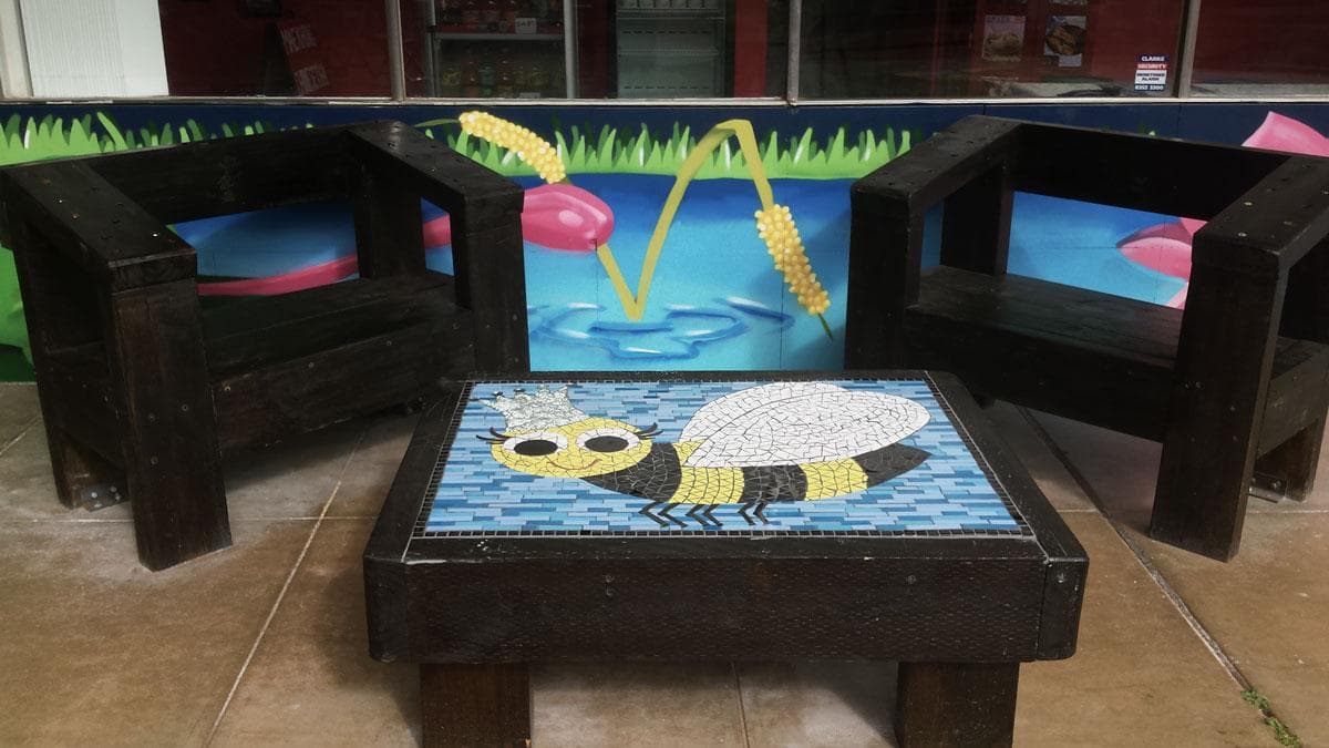 Two dark wooden chairs and a matching coffee table with a mosaic bee inlay